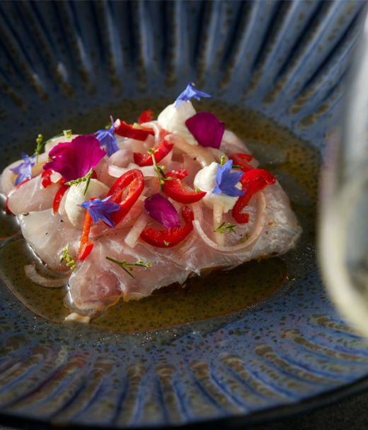 Ceviche van zeebaars met Chorizo olie, citroenroomkaas, bloemen en gemarineerde rode peper